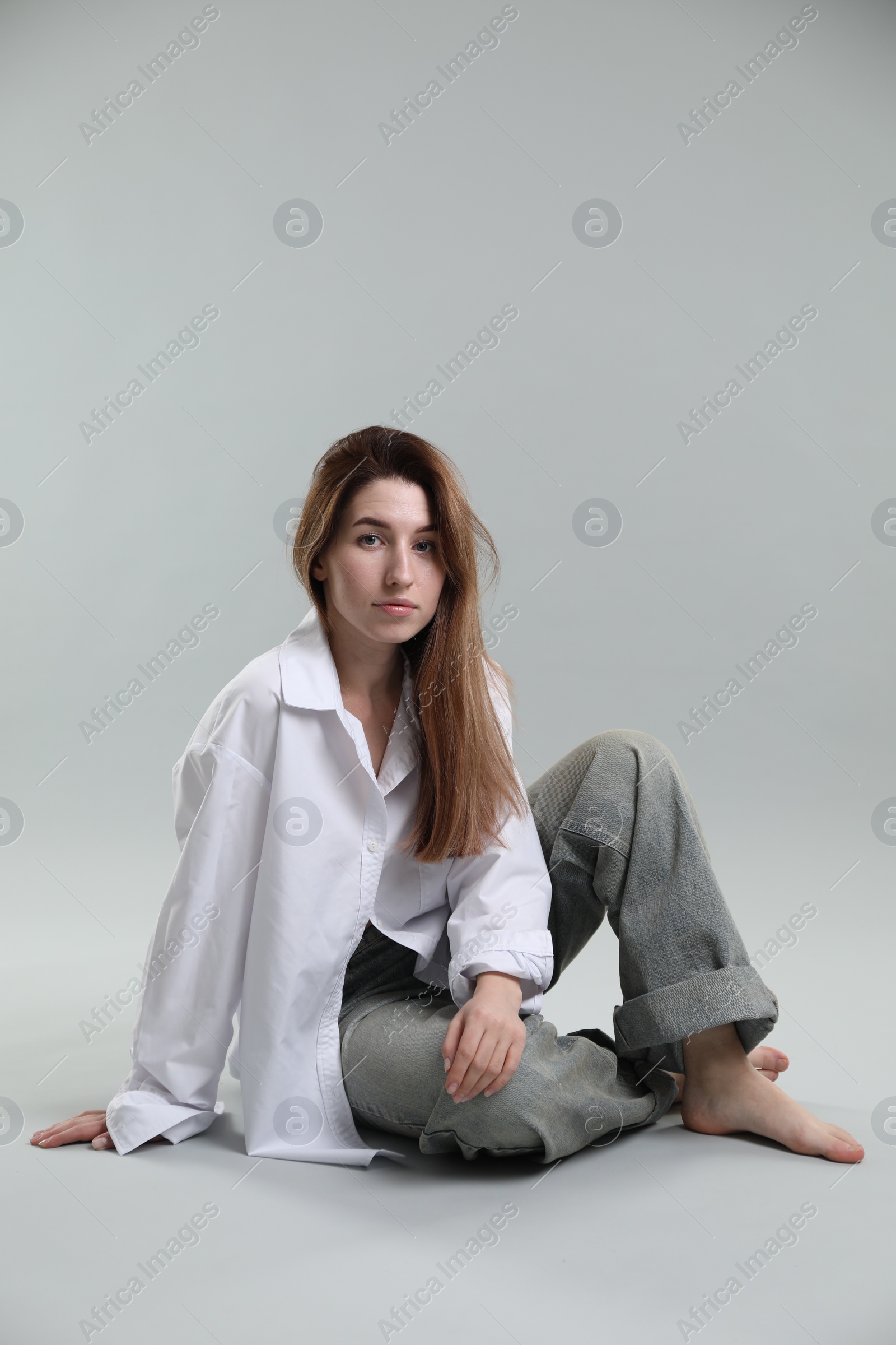 Photo of Beautiful young woman sitting on grey background