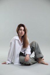 Photo of Beautiful young woman sitting on grey background