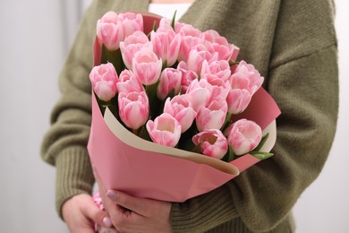 Woman with bouquet of beautiful fresh tulips on blurred background, closeup