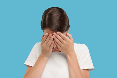 Photo of Resentful woman covering face with hands on light blue background