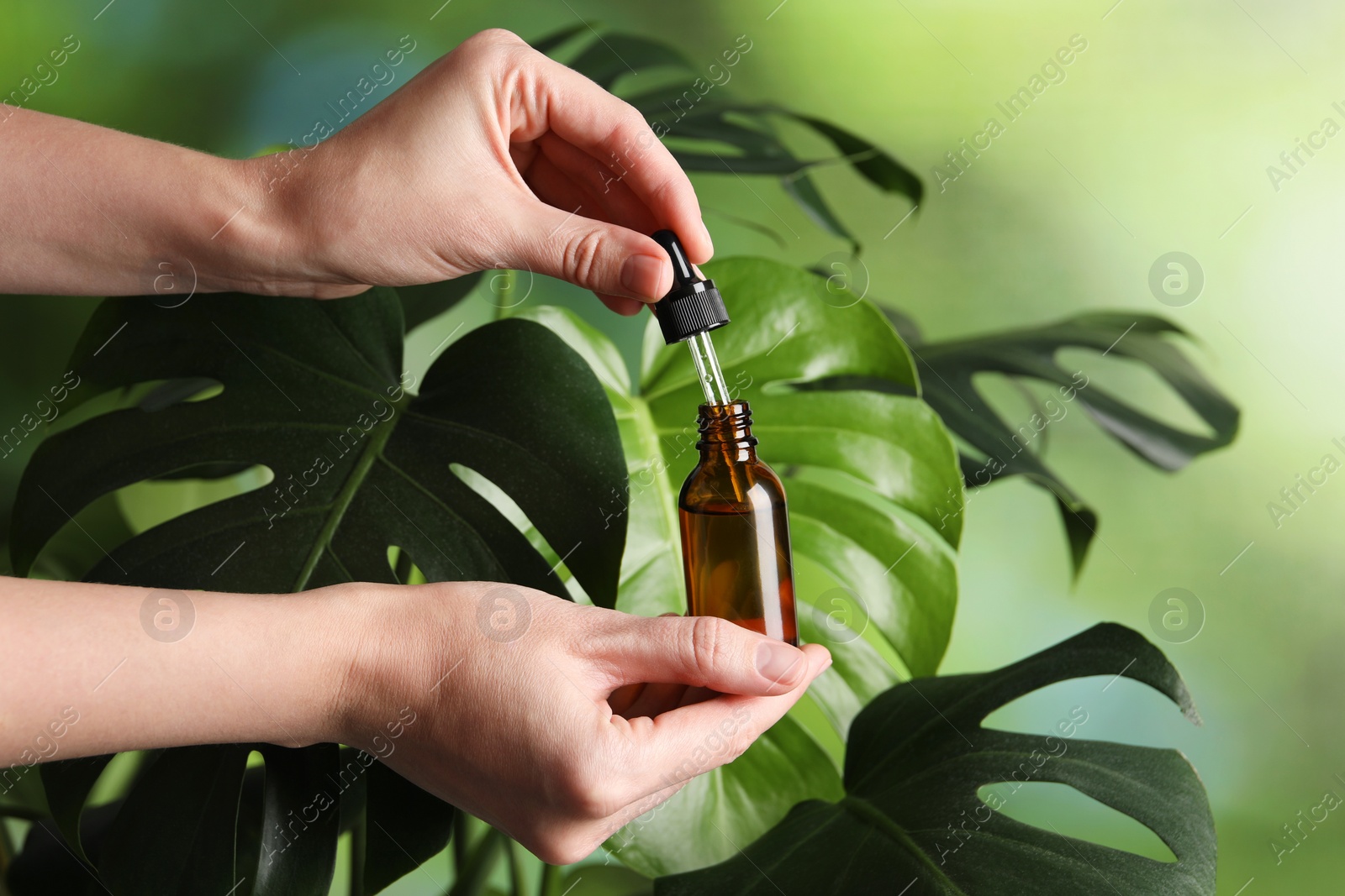 Photo of Woman with bottle of cosmetic serum and dropper on green background, closeup. Space for text