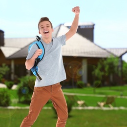 Image of Happy teenage boy jumping near house. School holidays