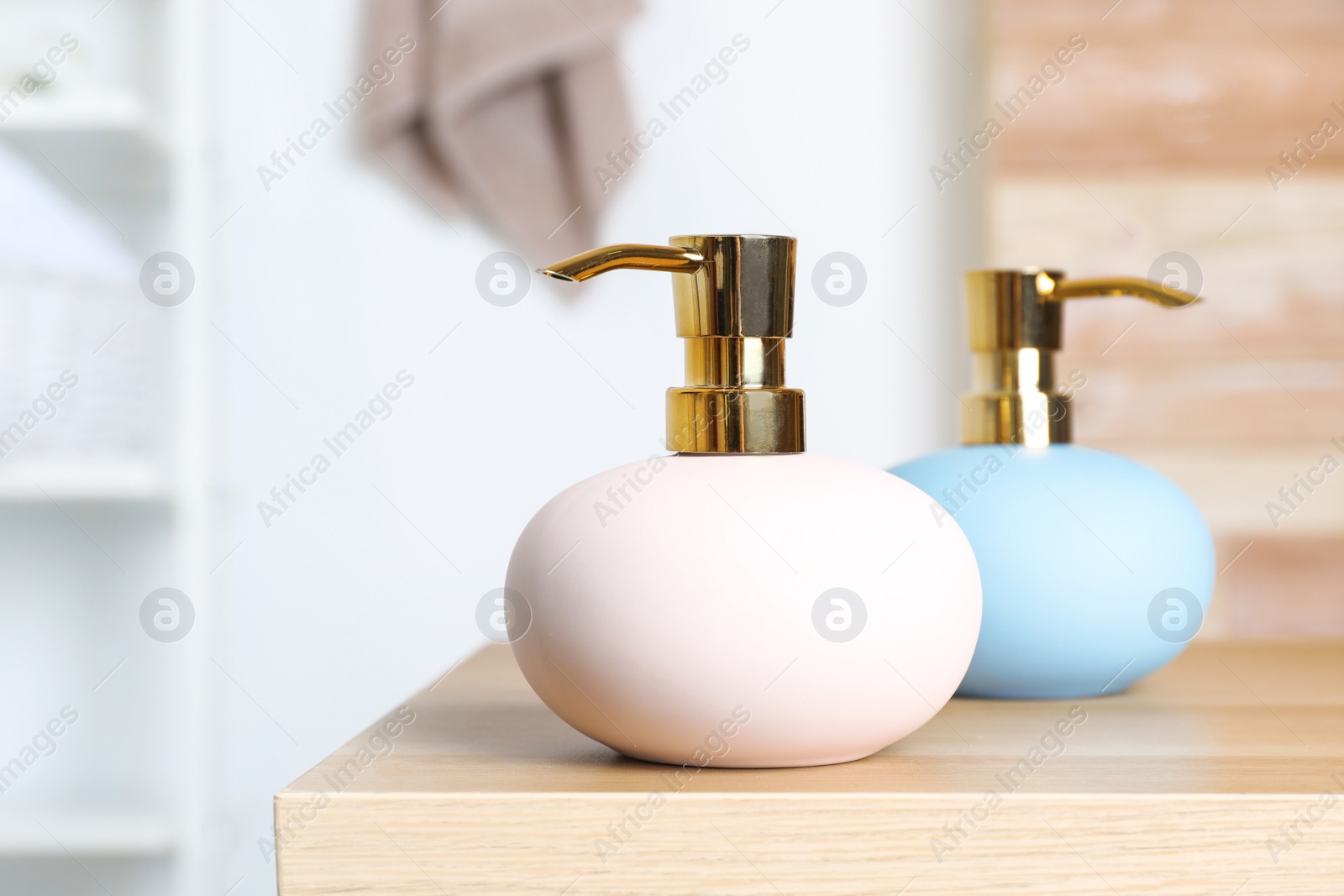 Photo of Stylish soap dispensers on table against blurred background. Space for text