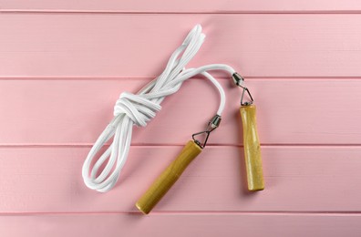 Photo of Skipping rope on pink wooden table, top view. Sports equipment