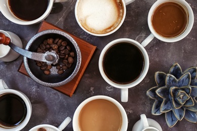 Photo of Cups of fresh aromatic coffee on grey background, top view