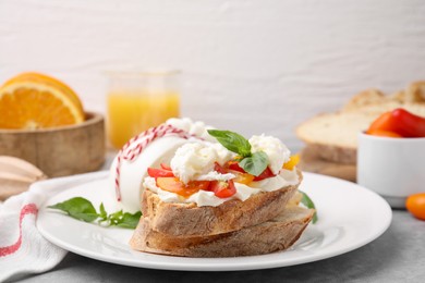 Photo of Delicious sandwich with burrata cheese and tomatoes on grey table, closeup. Space for text