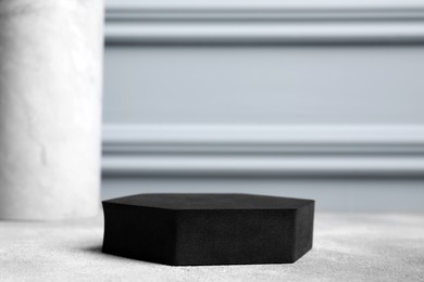Photo of Black geometric figure on light grey table, closeup and space for text. Stylish presentation for product