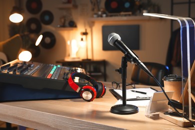 Photo of Microphone and professional mixing console on table in radio studio