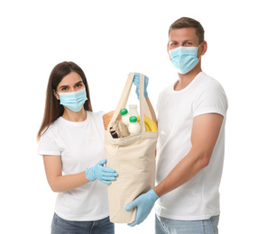 Photo of Volunteers in protective masks and gloves with products on white background. Aid during coronavirus quarantine