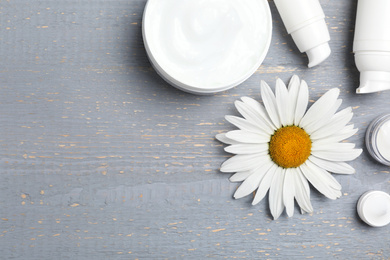 Photo of Flat lay composition with chamomile flower and cosmetic products on wooden table, space for text