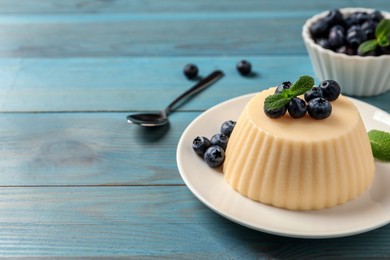 Delicious semolina pudding with blueberries on light blue wooden table, space for text