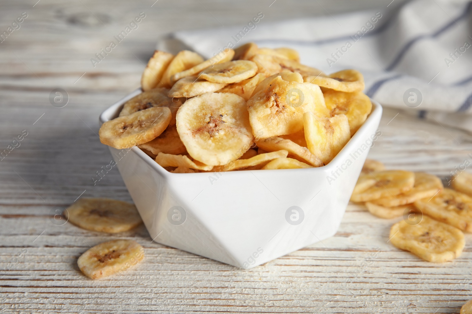 Photo of Bowl with sweet banana slices on wooden  table. Dried fruit as healthy snack