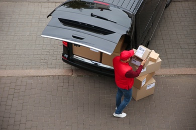 Photo of Courier with parcels near delivery van outdoors, above view