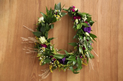 Photo of Beautiful wreath made of flowers and leaves on wooden background, top view