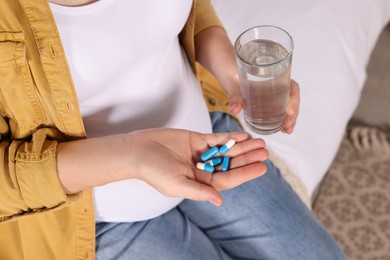 Photo of Pregnant woman taking pills on bed, closeup