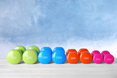 Photo of Many dumbbells for on table against color background. Fitness equipment
