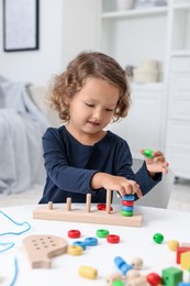 Motor skills development. Little girl playing with stacking and counting game at table indoors