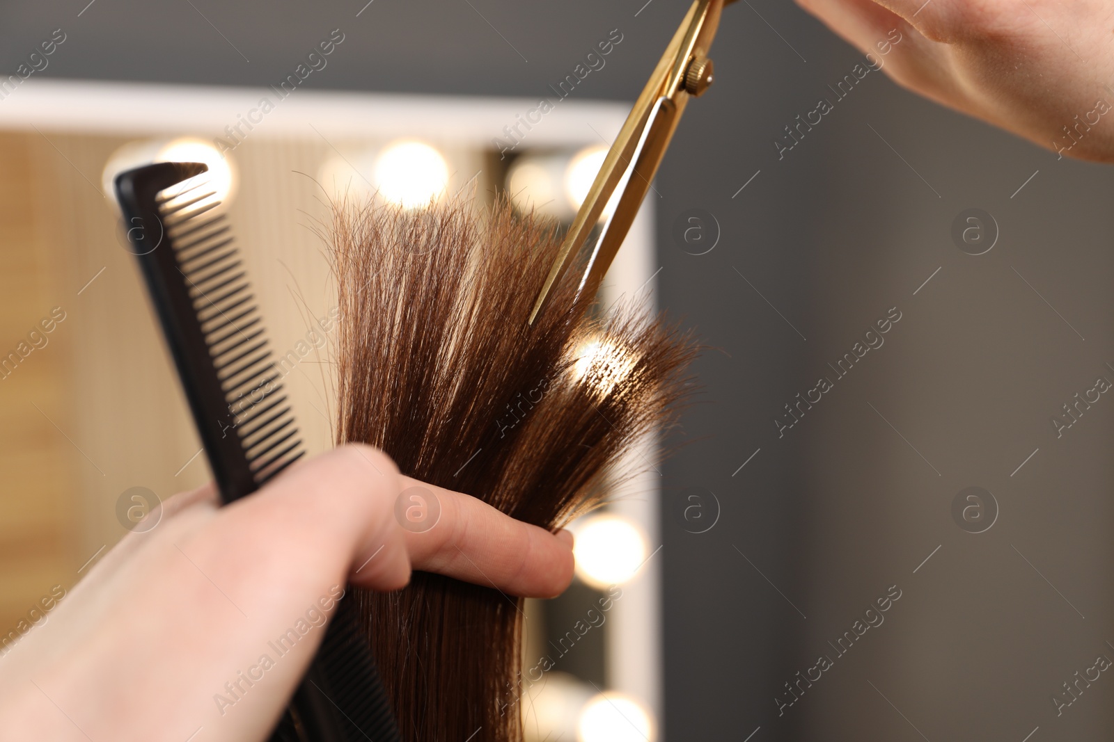 Photo of Hairdresser cutting client's hair with scissors in salon, closeup