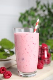 Photo of Glass of tasty raspberry smoothie on light table