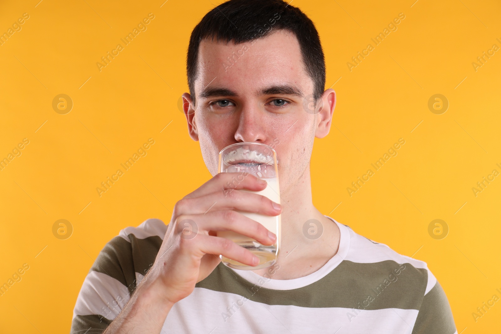 Photo of Milk mustache left after dairy product. Man drinking milk on orange background