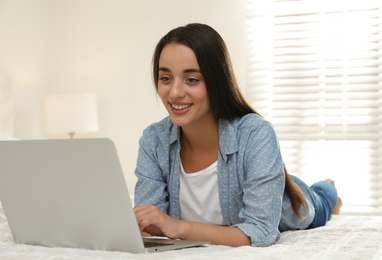 Woman using laptop for search on bed at home