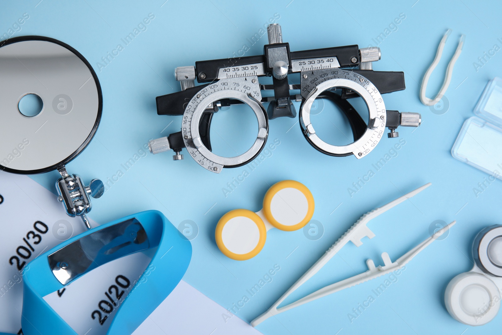 Photo of Different ophthalmologist tools on light blue background, flat lay