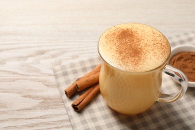 Photo of Delicious eggnog with cinnamon on wooden table, closeup. Space for text