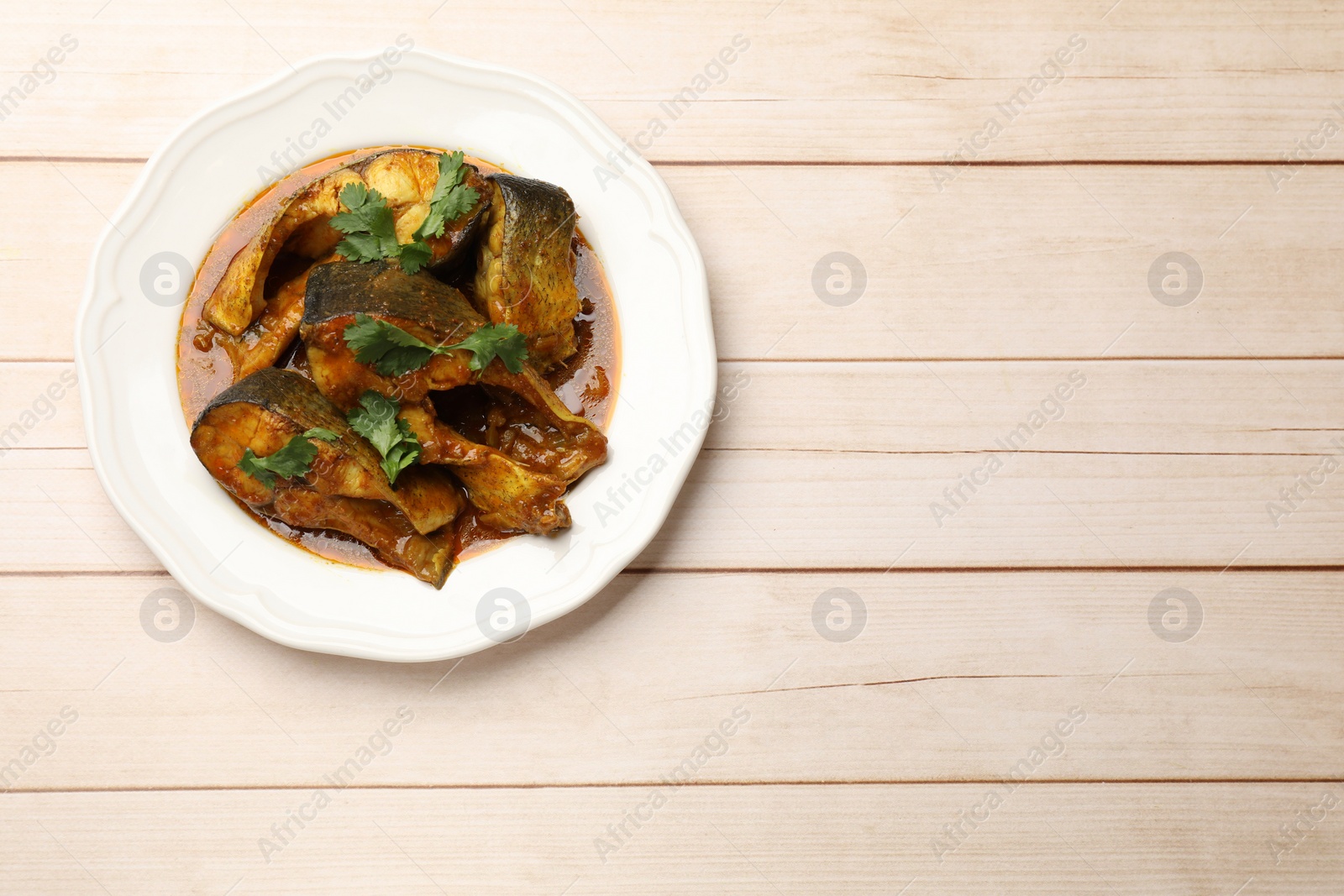 Photo of Tasty fish curry on white wooden table, top view. Space for text. Indian cuisine