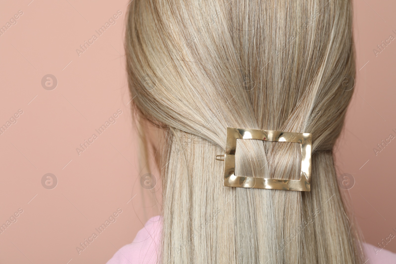 Photo of Young woman with beautiful gold hair clip on pink background, closeup