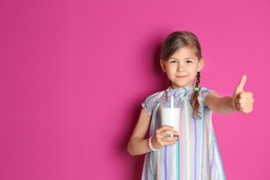 Cute little girl with glass of milk on color background