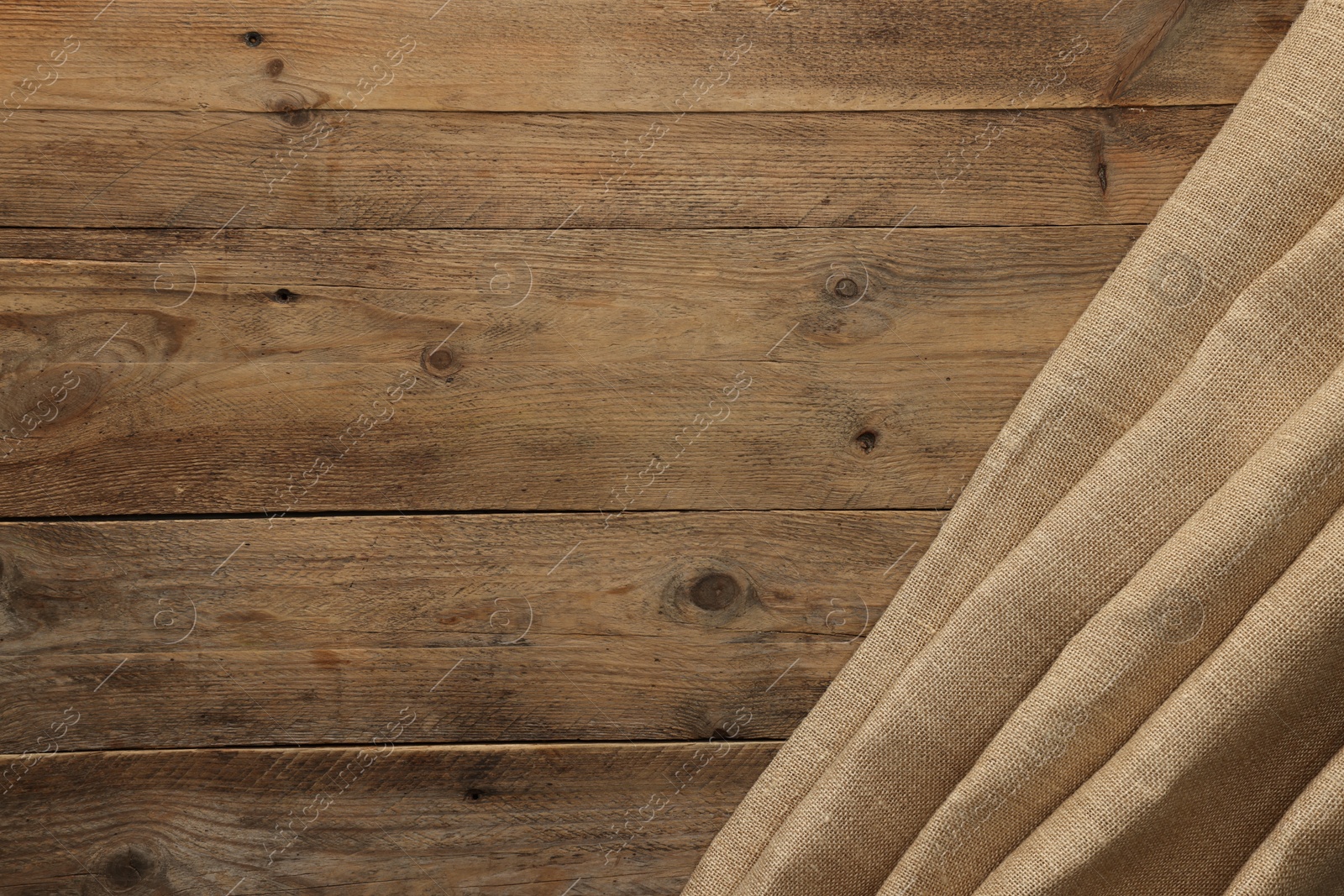 Photo of Burlap fabric on wooden table, top view. Space for text