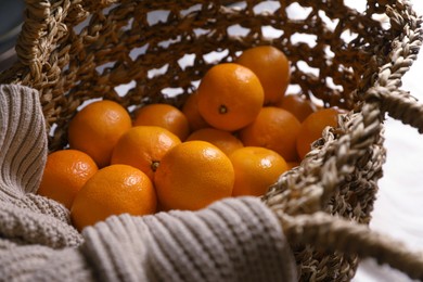 Net bag with many fresh ripe tangerines on white cloth, closeup