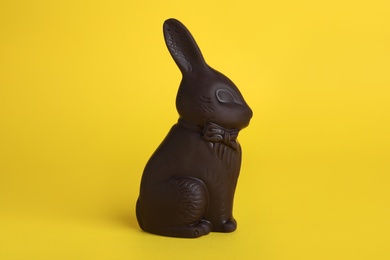 Photo of Dark chocolate bunny on yellow background. Easter celebration