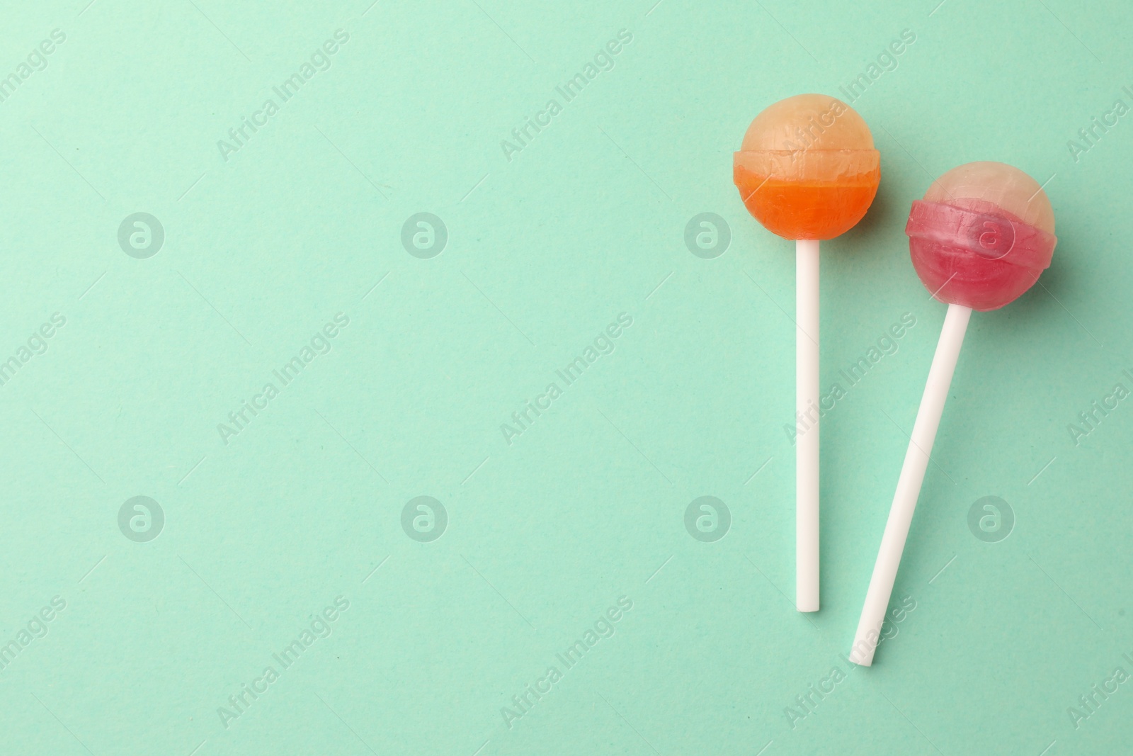 Photo of Tasty lollipops on turquoise background, flat lay. Space for text