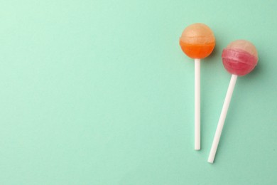 Photo of Tasty lollipops on turquoise background, flat lay. Space for text