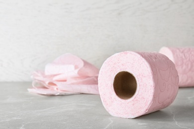 Photo of Roll of toilet paper on grey table. Space for text