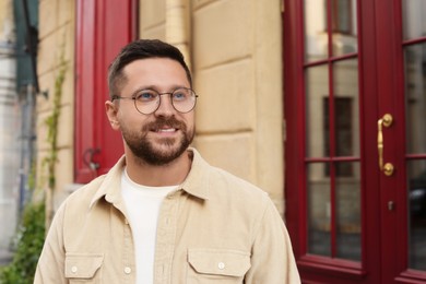 Portrait of handsome bearded man in glasses outdoors, space for text