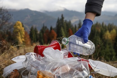 Woman collecting garbage in nature, closeup of hand with crumpled bottle