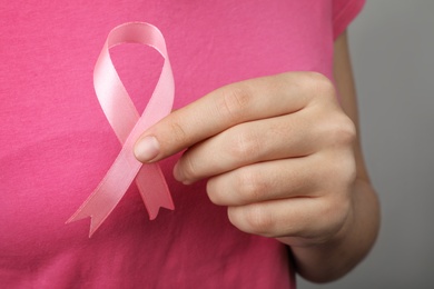 Woman holding pink ribbon, closeup. Breast cancer awareness