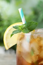 Photo of Delicious iced tea in glass outdoors, closeup