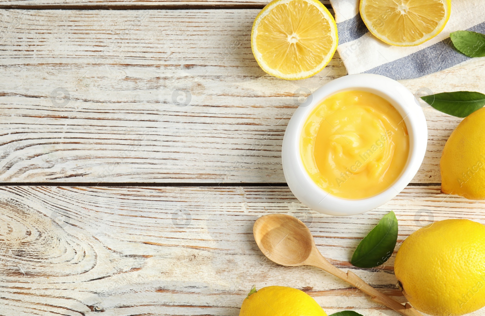 Photo of Delicious lemon curd in bowl on white wooden table, flat lay. Space for text