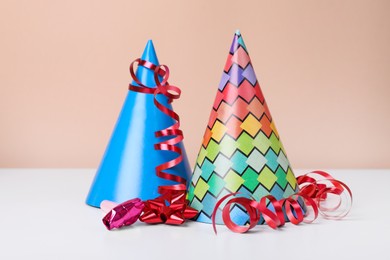 Photo of Colorful party hats, streamers and blower on white table. Birthday celebration