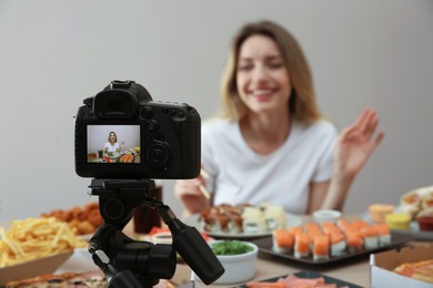 Food blogger recording eating show against beige background, focus on camera screen. Mukbang vlog