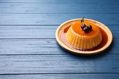 Delicious pudding with caramel and cherries on blue wooden table. Space for text