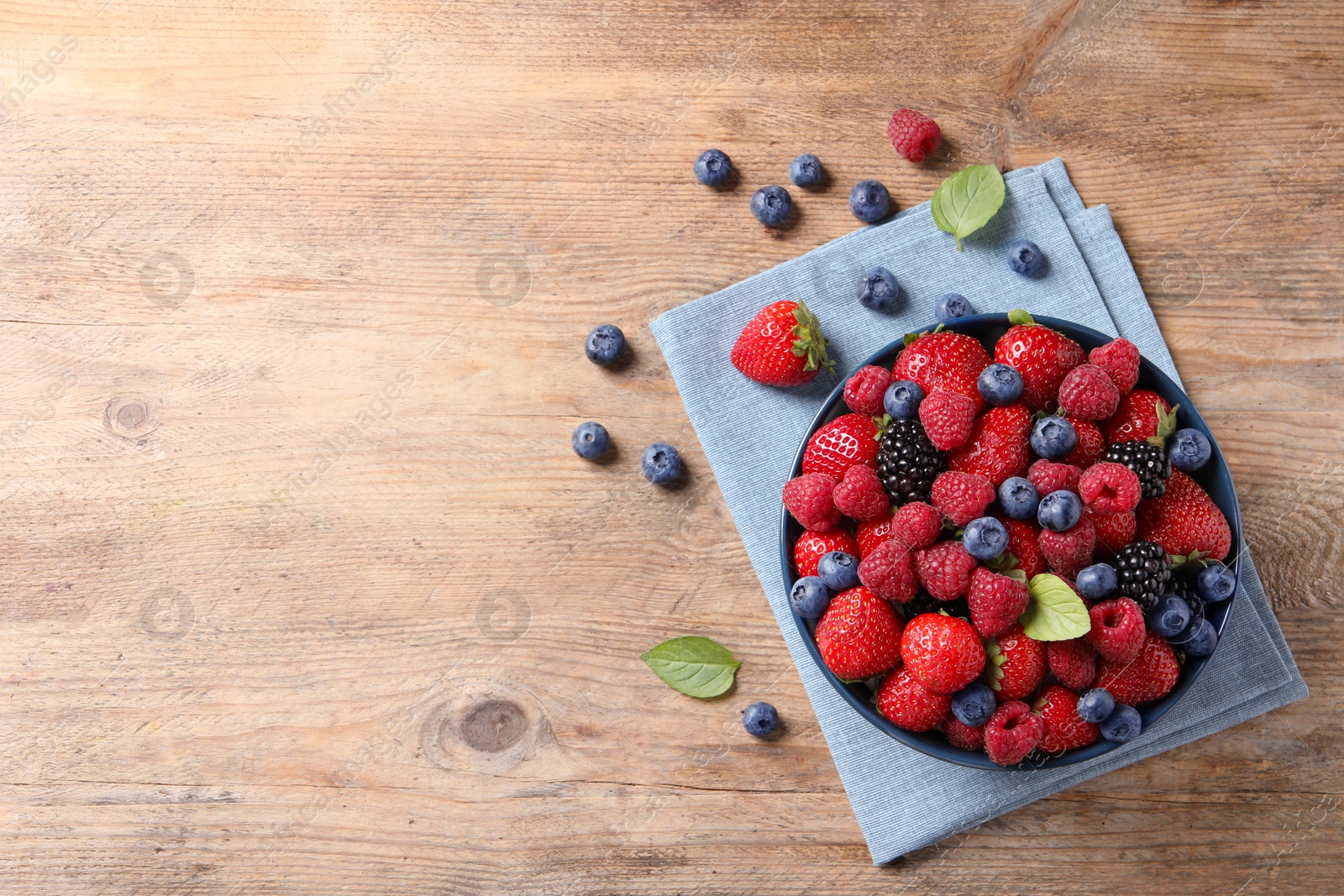 Photo of Different fresh ripe berries on wooden table, flat lay. Space for text