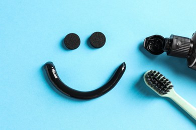 Photo of Flat lay composition with charcoal toothpaste on light blue background