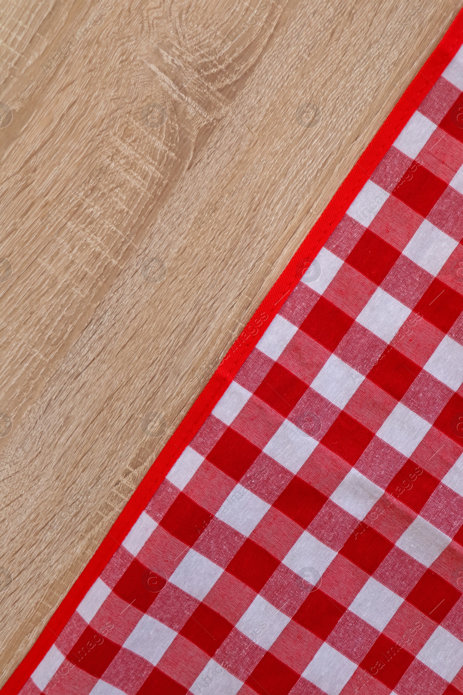 Photo of Checkered picnic cloth on wooden table, top view. Space for text