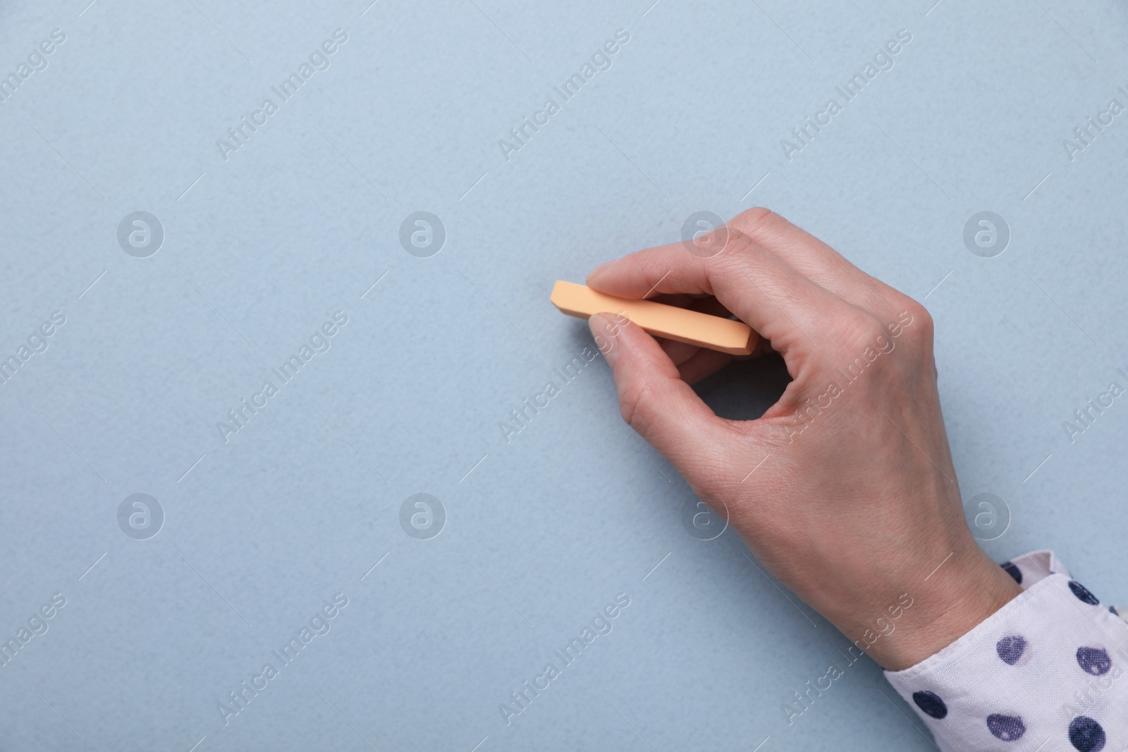 Photo of Woman drawing on light blue paper with pastel, top view. Space for text