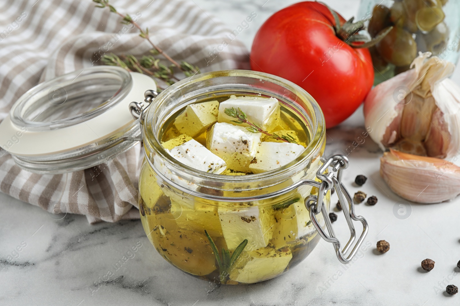 Photo of Composition with pickled feta cheese in jar on white marble table