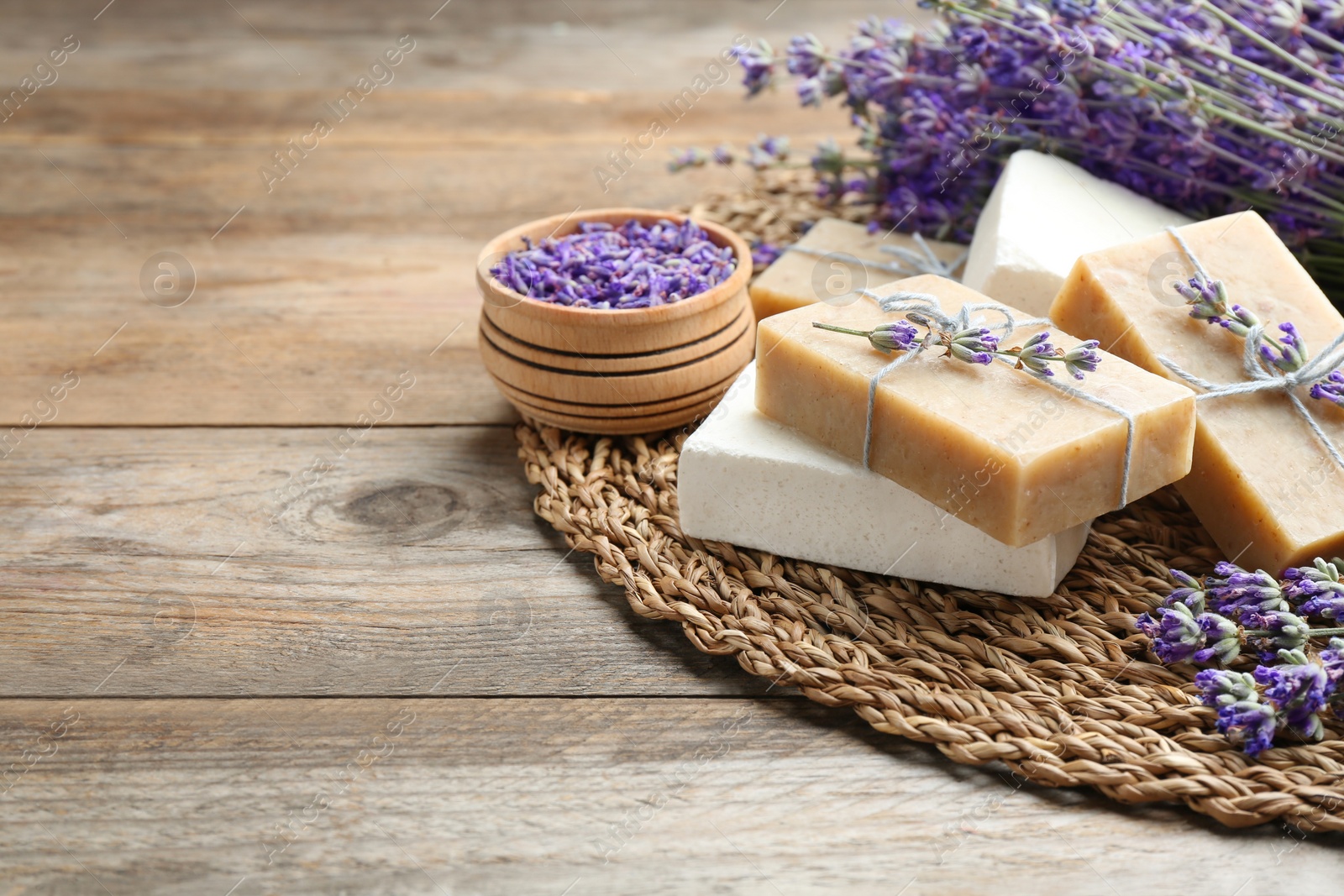 Photo of Handmade soap bars with lavender flowers on brown wooden table. Space for text